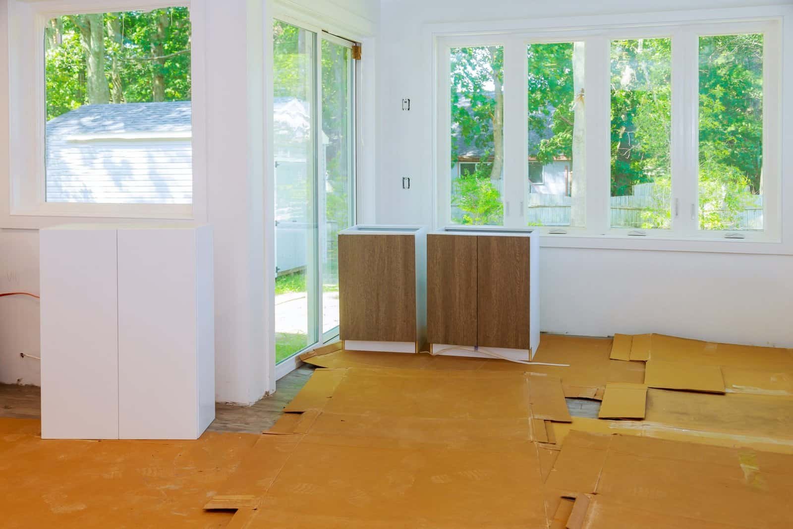 Bright sunlit room with large windows and ongoing flooring renovation.