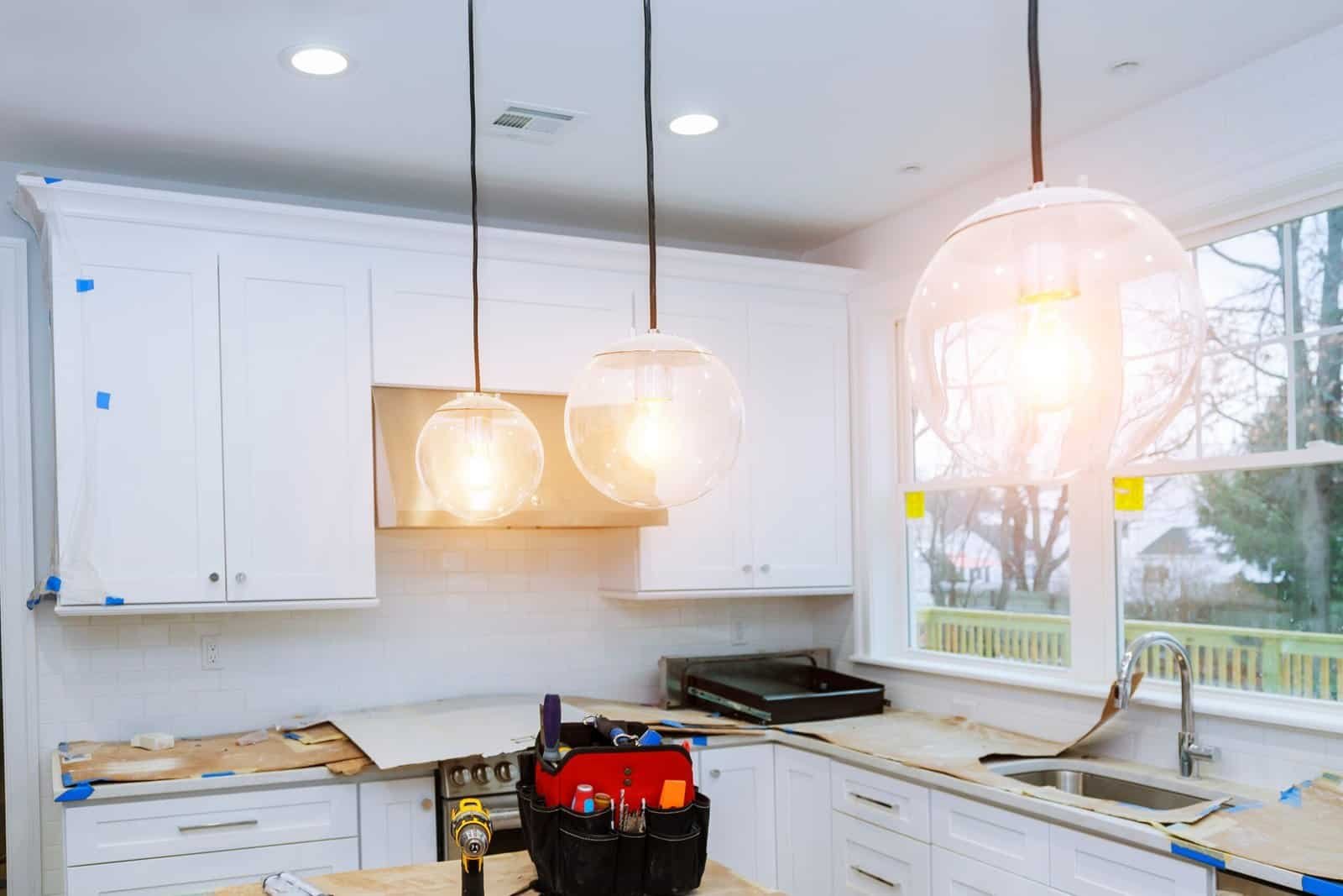 Bright modern kitchen with white cabinets and pendant lighting.