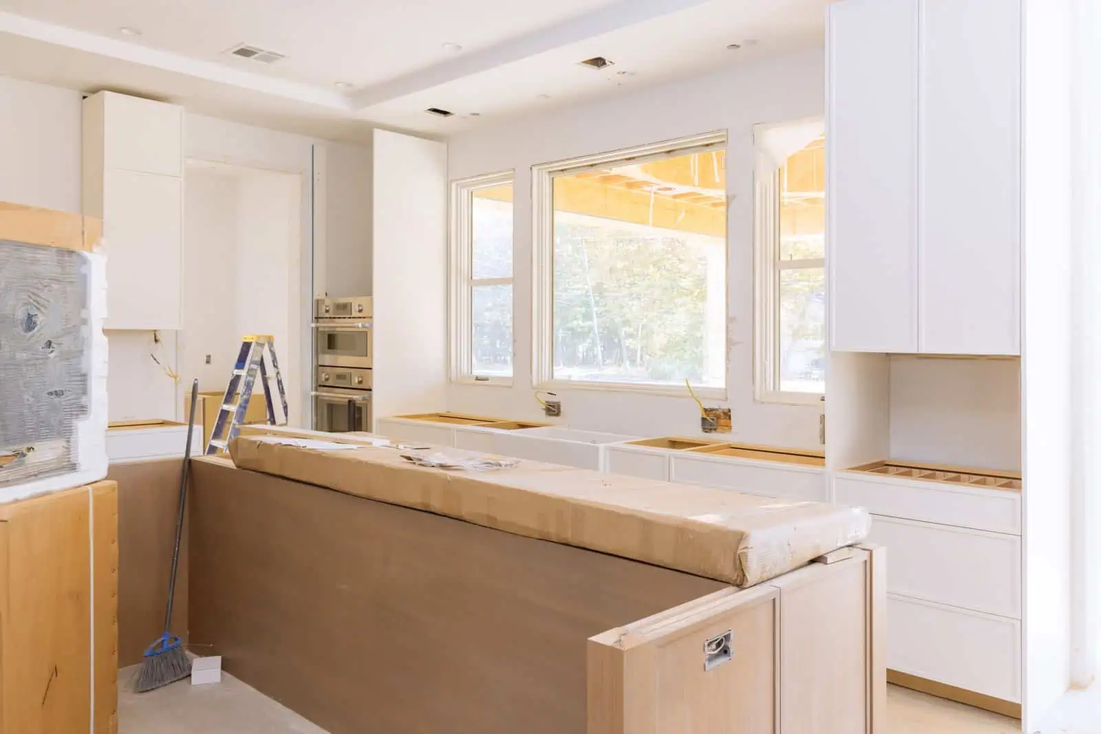 Newly renovated kitchen with white cabinets and large windows.