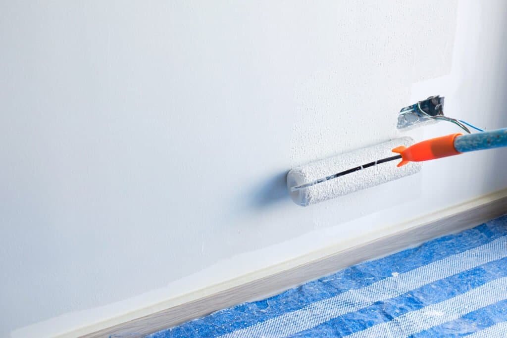 Painting a wall with a roller brush in a home renovation project.