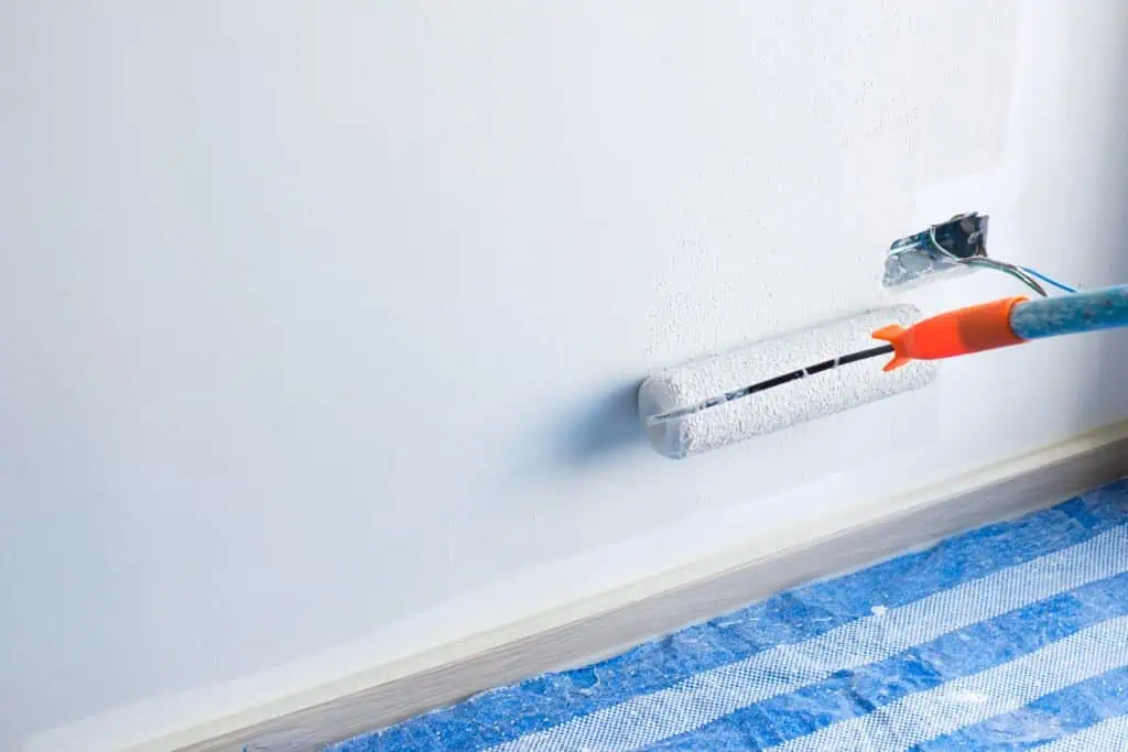 Painting a wall with a roller brush in a home renovation project.