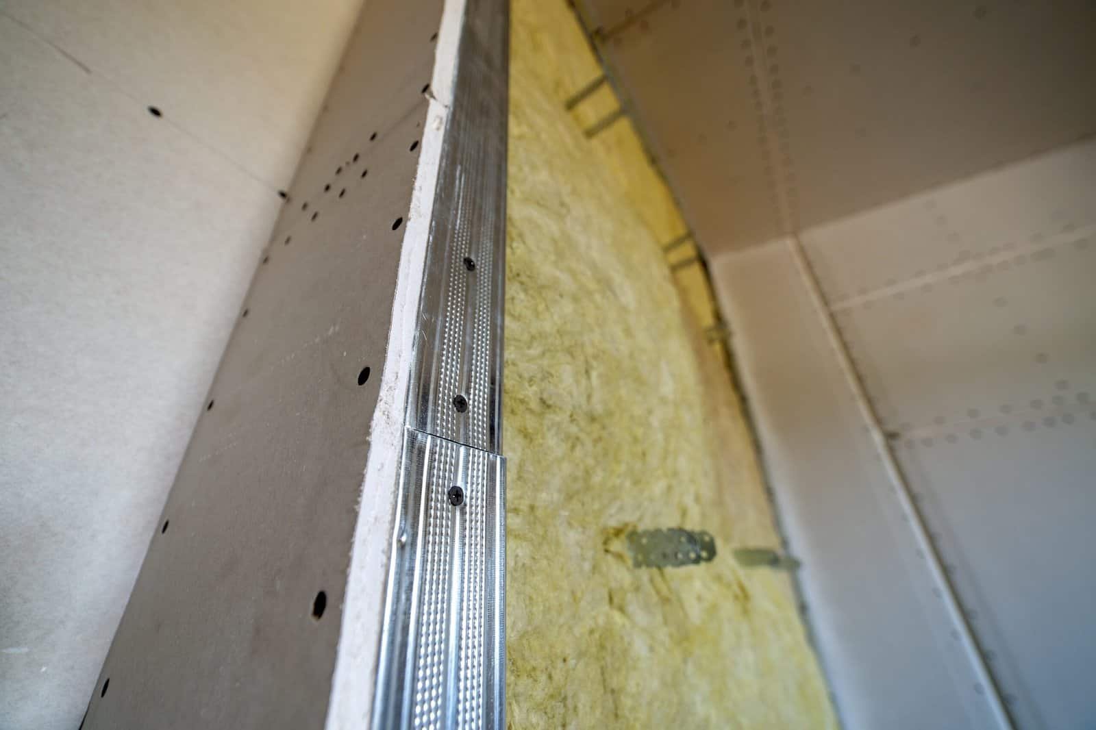 Close-up of wall framing and insulation installation in home renovation.
